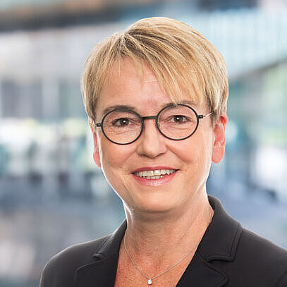 Frau Boelsems mit Brille in einem modernen, hellen Raum.