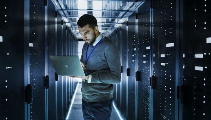 Risikofeld Cyber: Mann mit Laptop in einem Rechenzentrum