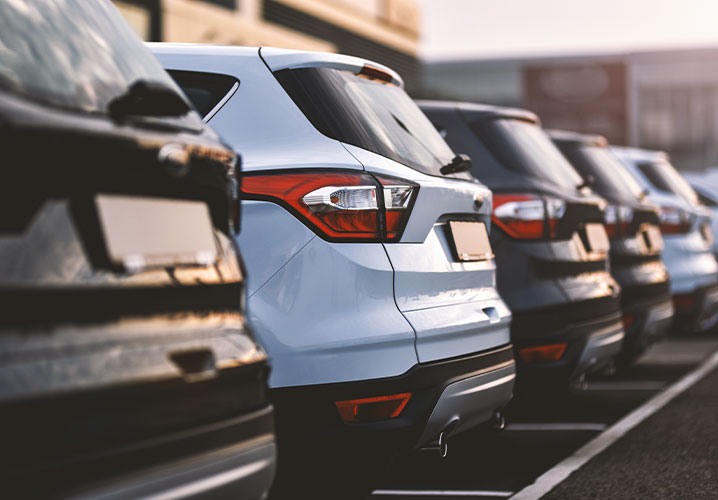 Reihe von Autos auf einem Parkplatz, mit einem weißen SUV im Fokus, vermittelt ruhige Alltagsszene.