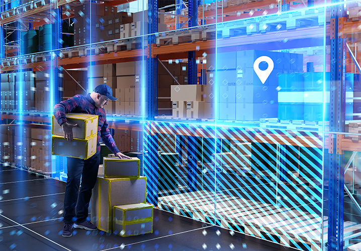 Lagerarbeiter hebt Kartons in einer modernen Lagerhalle, umgeben von Regalen und einem technischen Ambiente.