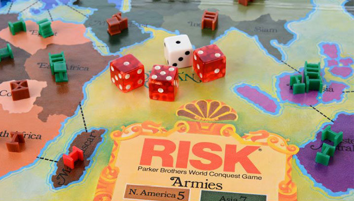 Detailreiche Spielszene eines Risiko-Spiels mit bunten Armeen und Würfeln, vermittelt strategische Spannung.