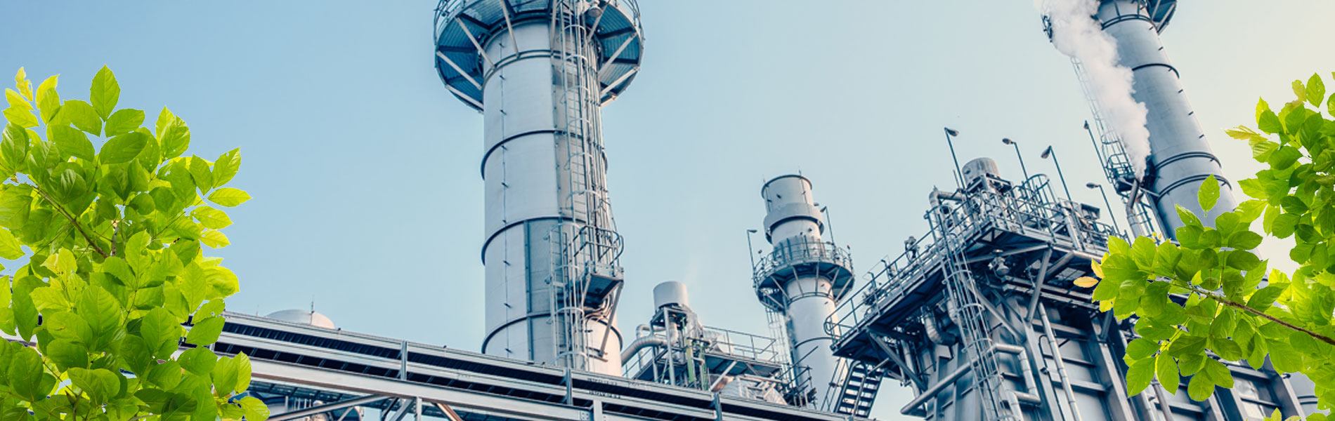 Industrieanlagen unter klarem Himmel, umgeben von frischem Grün, symbolisieren Fortschritt und Umweltbewusstsein.