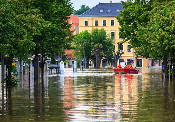 Regenschirm unter starkem Regen mit Bäumen im Hintergrund.