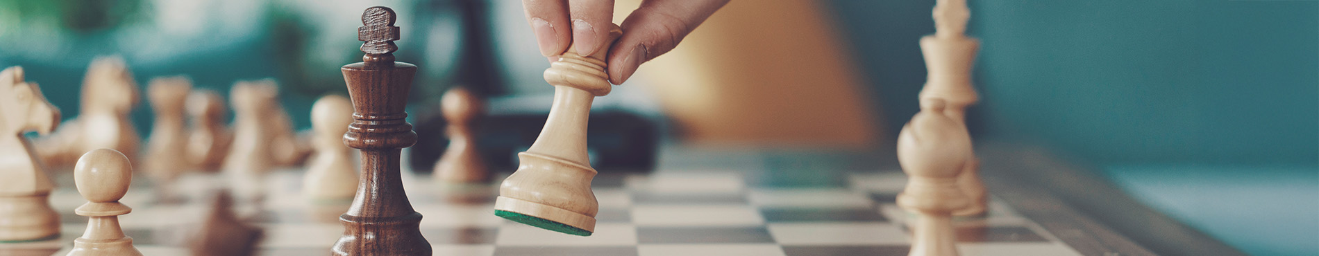 Eine Hand bewegt eine Schachfigur über das Schachbrett, Spannung und Konzentration in der Luft.