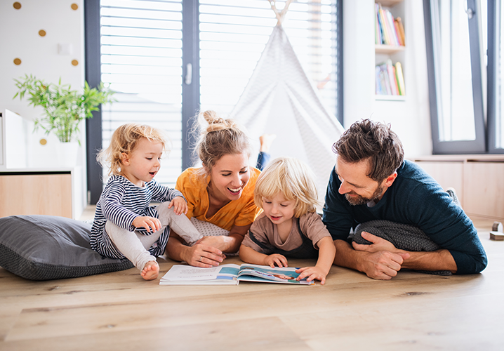 privater Versicherungsbereich: eine Familie liest zusammen auf dem Boden