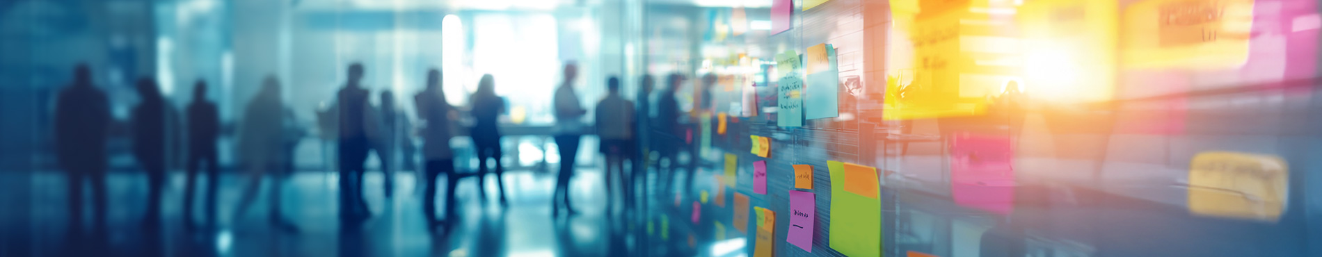 Bunte Haftnotizen an einer Glaswand, unterstützt durch Benefit Beratung, die kreatives Brainstorming und Teamarbeit in einem modernen Büro darstellen.