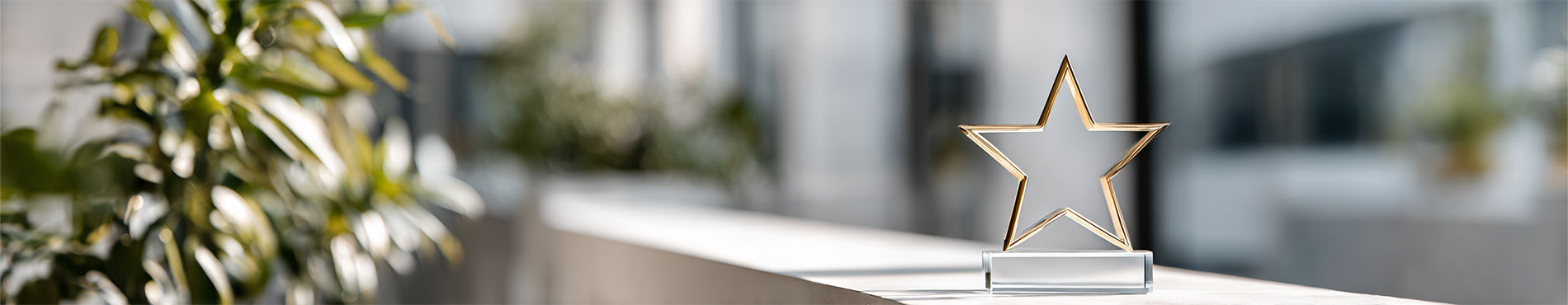 Ein goldener Stern auf einem weißen Tisch, umgeben von modernen Pflanzen. Eine Atmosphäre von Erfolg und Ehrung.