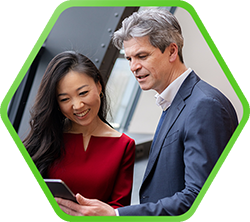 Ein lächelndes Paar betrachtet gemeinsam ein Tablet in einem modernen Raum, vermittelt Freude und Zusammenarbeit.