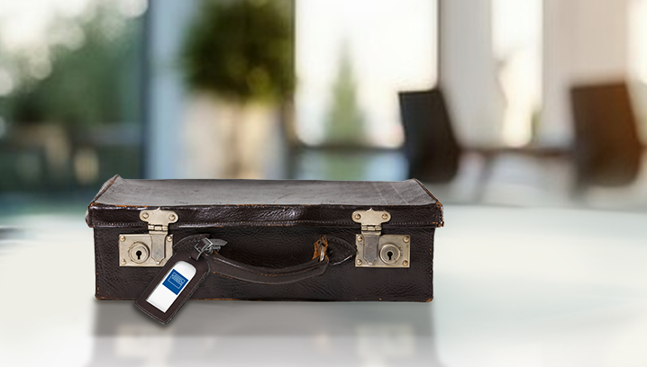 Brauner Lederkoffer mit einem Funk Anhänger liegend auf einem weißen Tisch