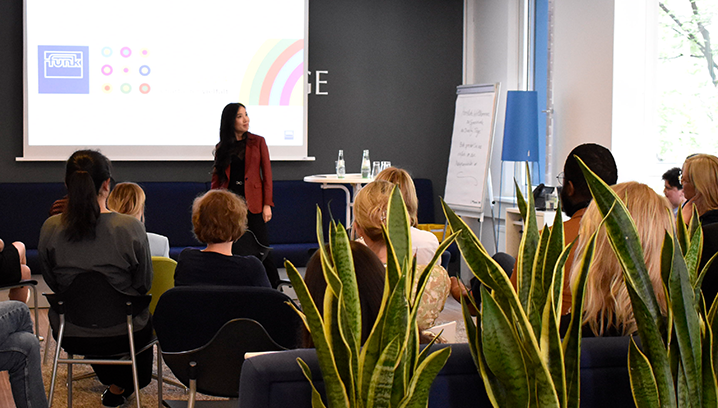 Eine Präsentation von Wanlu Wei in einem modernen Raum, mit Zuhörern, die aufmerksam der Rednerin folgen. 