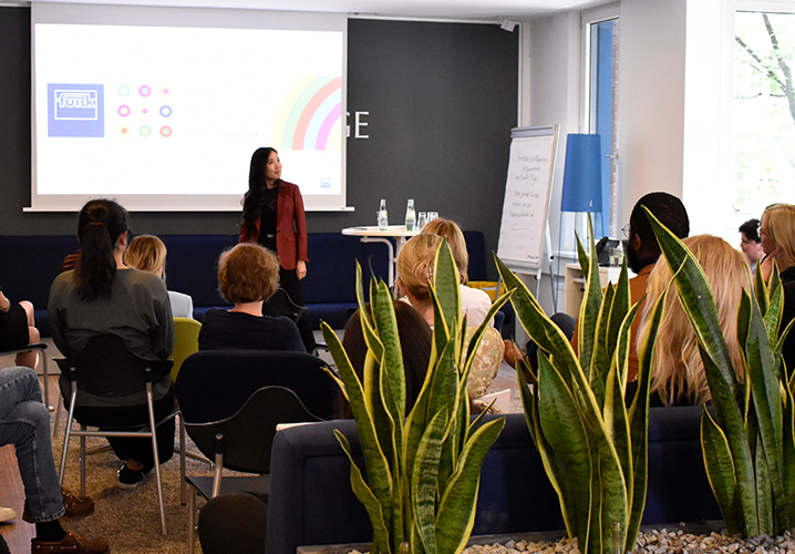 Eine Präsentation von Wanlu Wei in einem modernen Raum, mit Zuhörern, die aufmerksam der Rednerin folgen. 