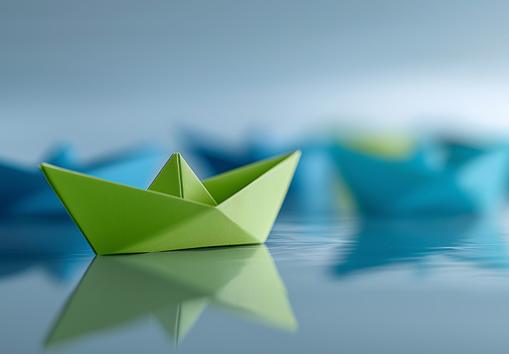 Ein grünes Origami-Boot schwimmt ruhig im Wasser, umgeben von blauen Booten, friedliche Stimmung.