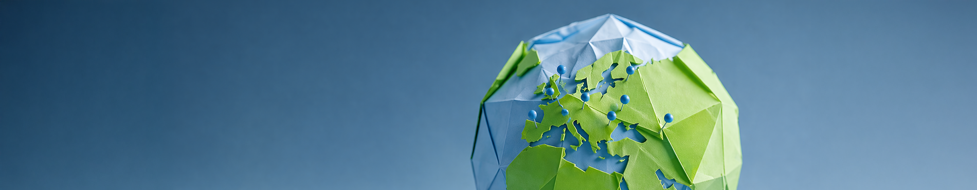 Papiermodell der Erde in Blau und Grün auf sanftem Hintergrund, symbolisiert Umweltbewusstsein und Kreativität.