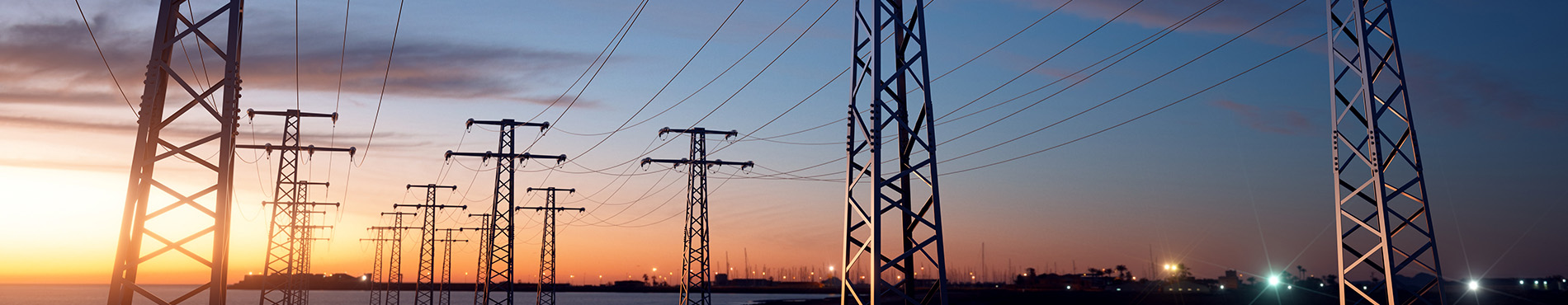 Strommasten silhouettieren sich vor einem bunten Sonnenuntergang, vermitteln technologische Atmosphäre.