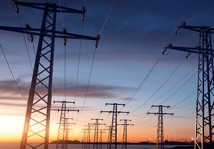 Strommasten silhouettieren sich vor einem bunten Sonnenuntergang, vermitteln technologische Atmosphäre.