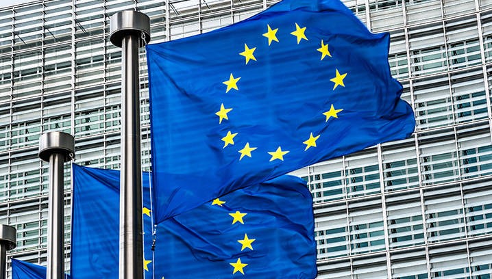 Europaflaggen wehen vor modernen Gebäuden, Symbol für Einheit und Zusammenarbeit in der Europäischen Union.