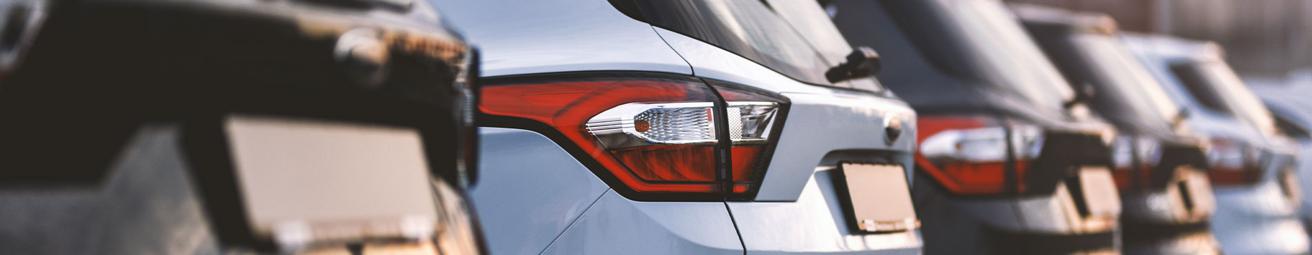 Reihe von Autos auf einem Parkplatz, mit einem weißen SUV im Fokus, vermittelt ruhige Alltagsszene.